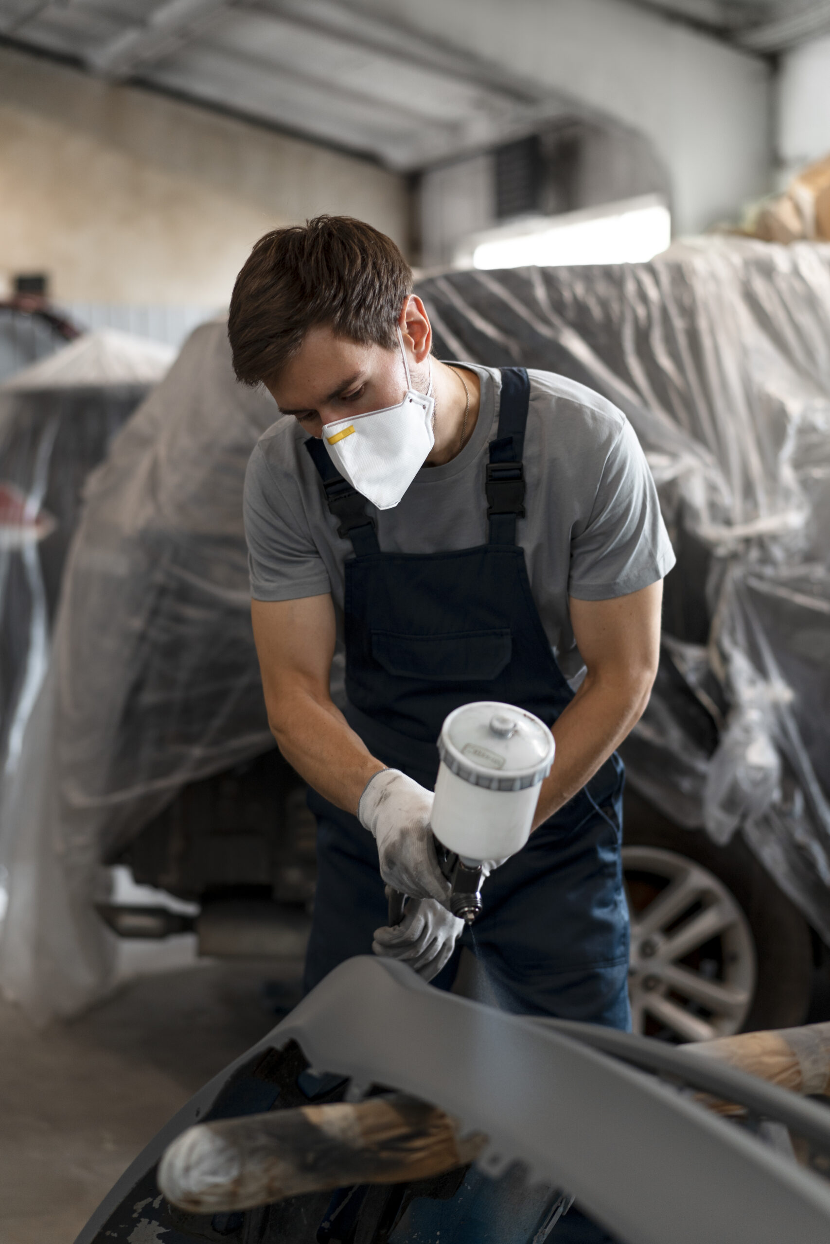 pintor masculino en overoles haciendo su trabajo en la tienda de autos